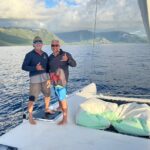 Friends on a yacht during multi-day sailing along Molokai coastline.